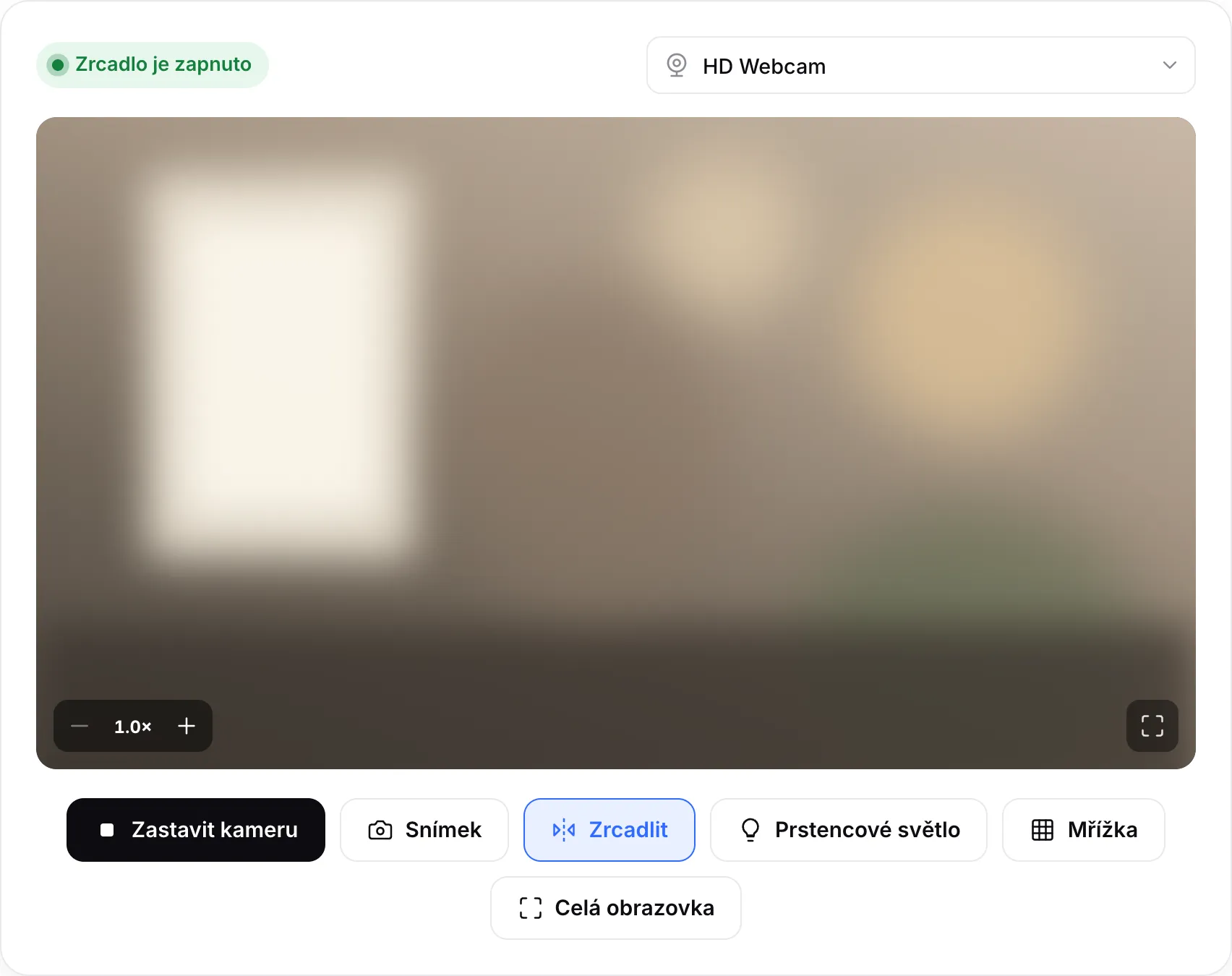 Spuštěné zrcadlo z webkamery se stavem „Zrcadlo je zapnuto“, tlačítky zoomu na obrazu a tlačítkem Prstencové světlo